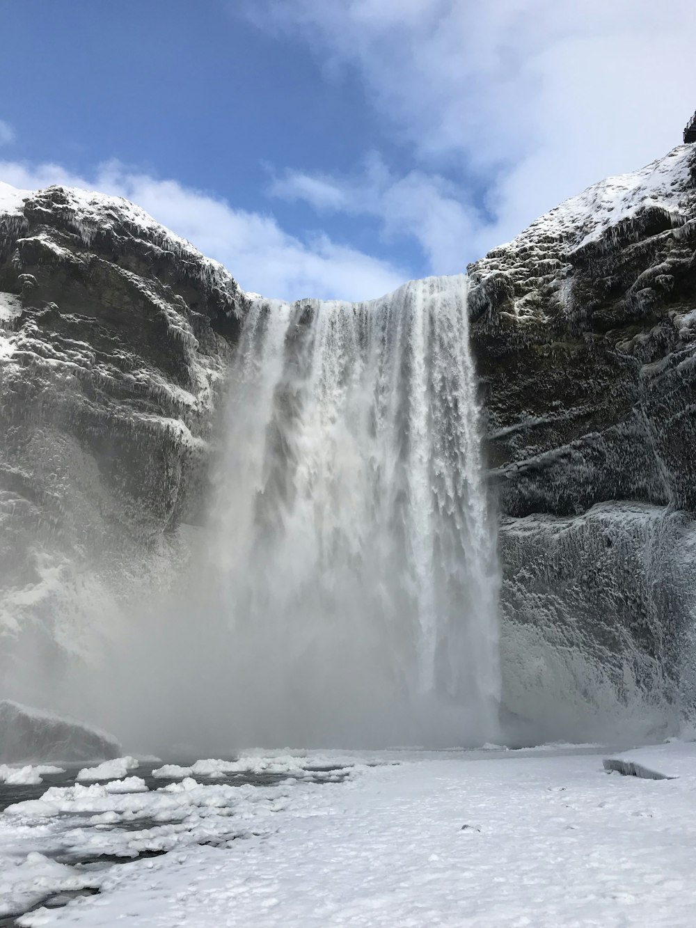 a large waterfall with snow on the ground
