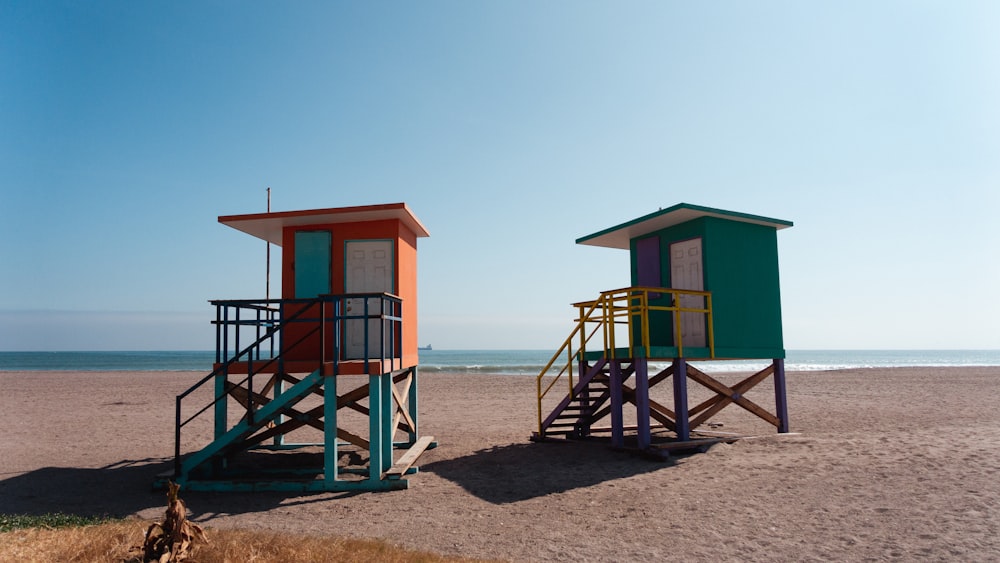 a couple of beach huts sitting on top of a sandy beach