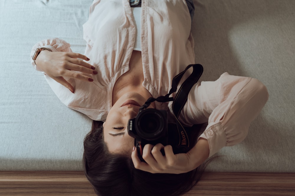 a woman laying on the floor holding a camera