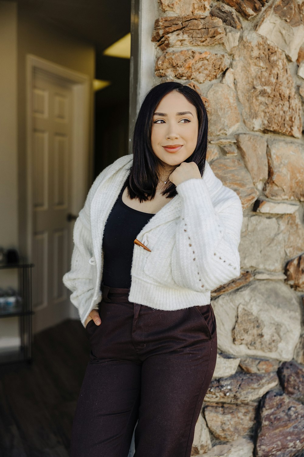 a woman standing in front of a stone wall