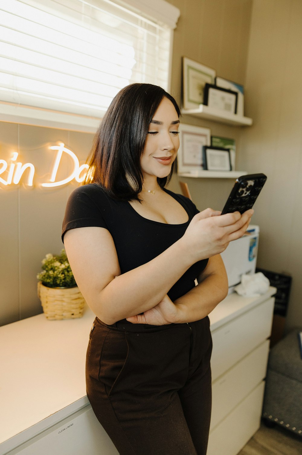 a woman standing in front of a counter holding a cell phone