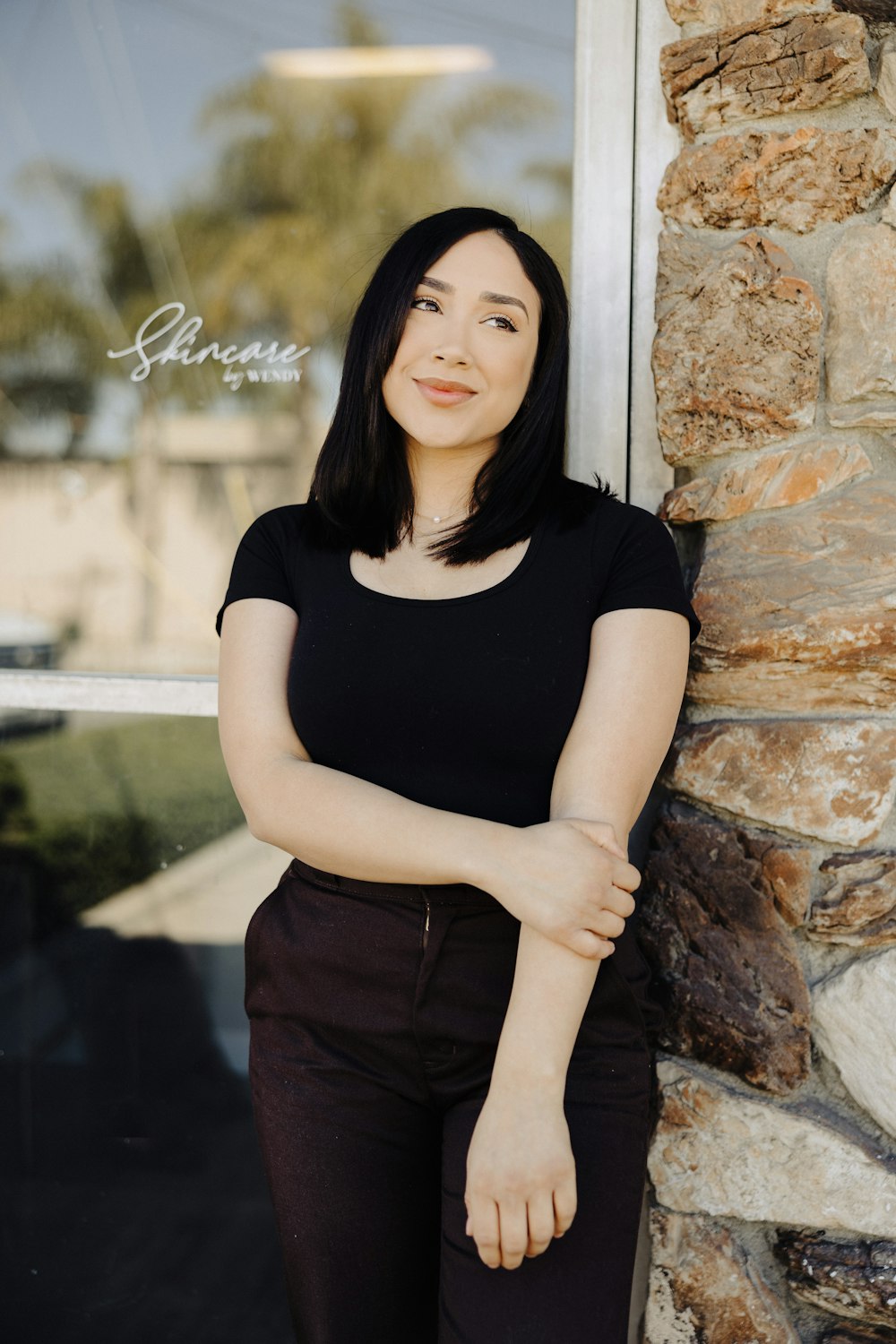 a woman leaning against a stone wall in front of a window