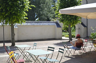 a woman sitting in a chair under an umbrella
