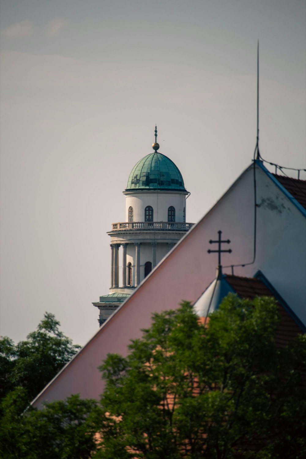 a white building with a green dome and a cross on top