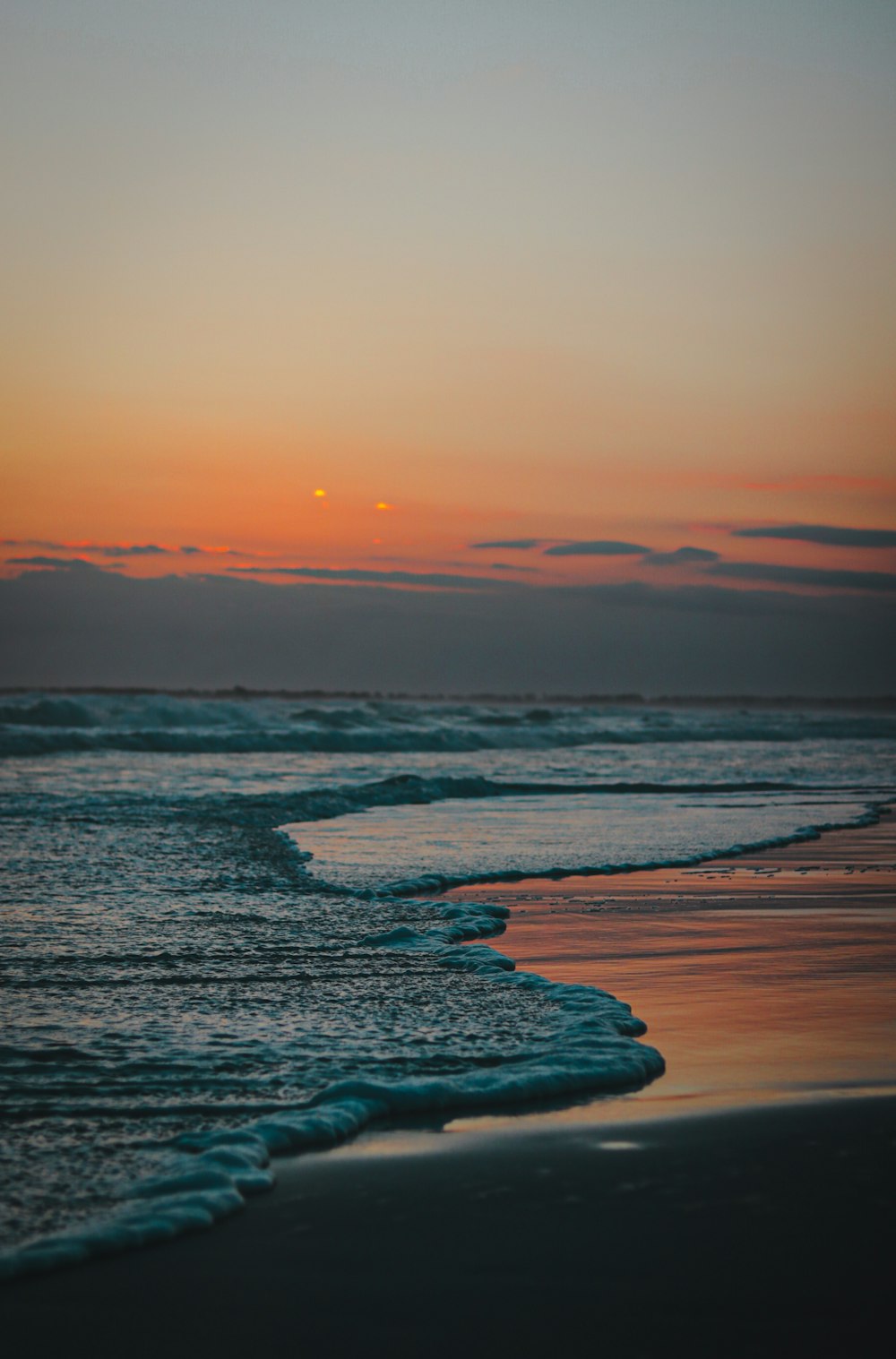 the sun is setting over the water at the beach