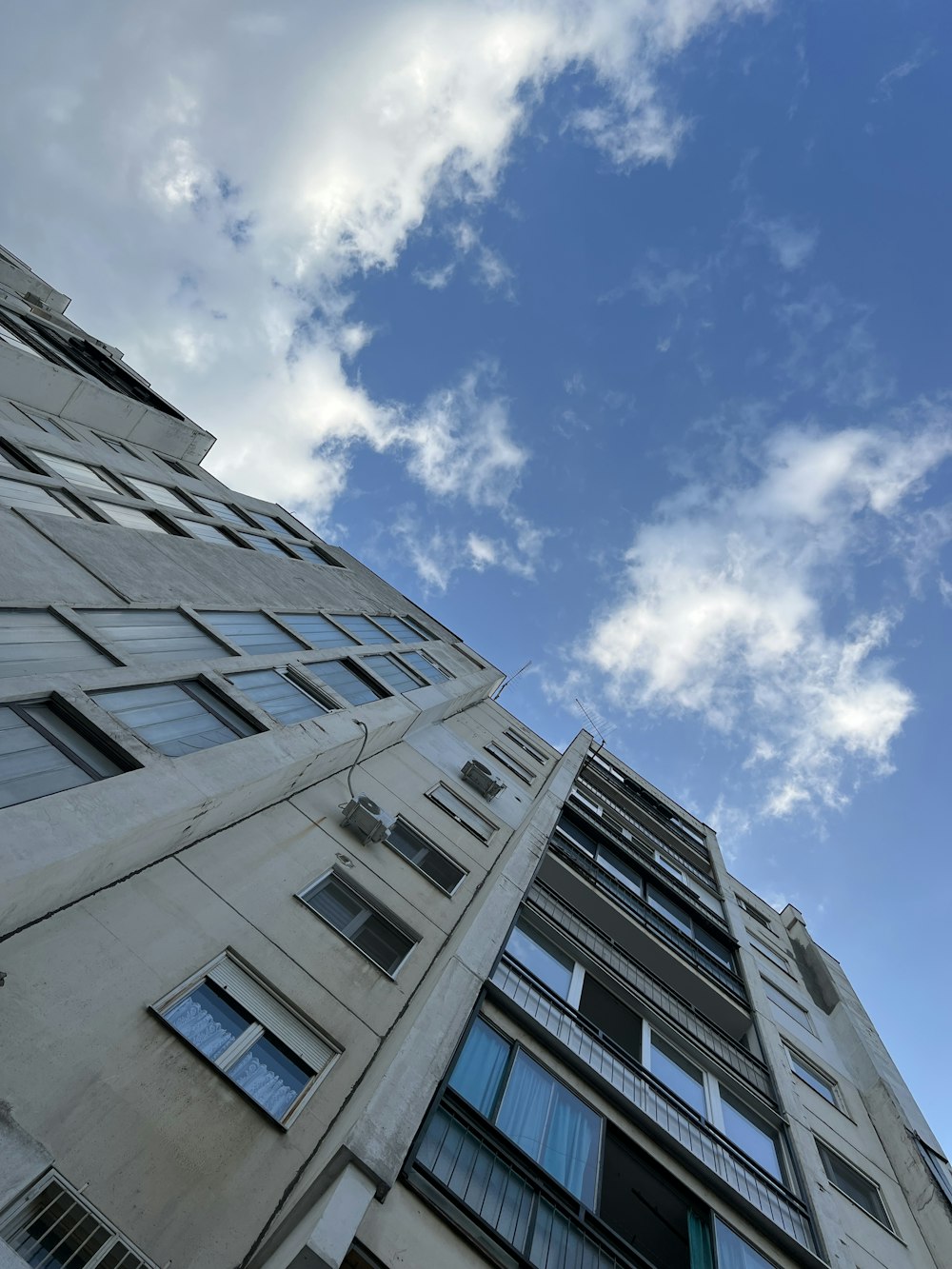 a tall building with lots of windows under a cloudy blue sky