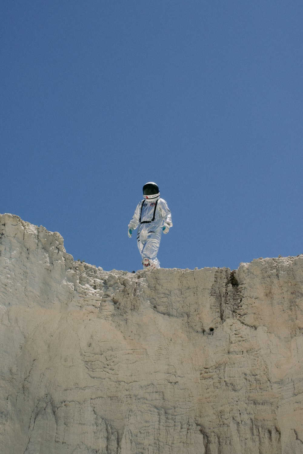 a man in a white suit standing on top of a cliff
