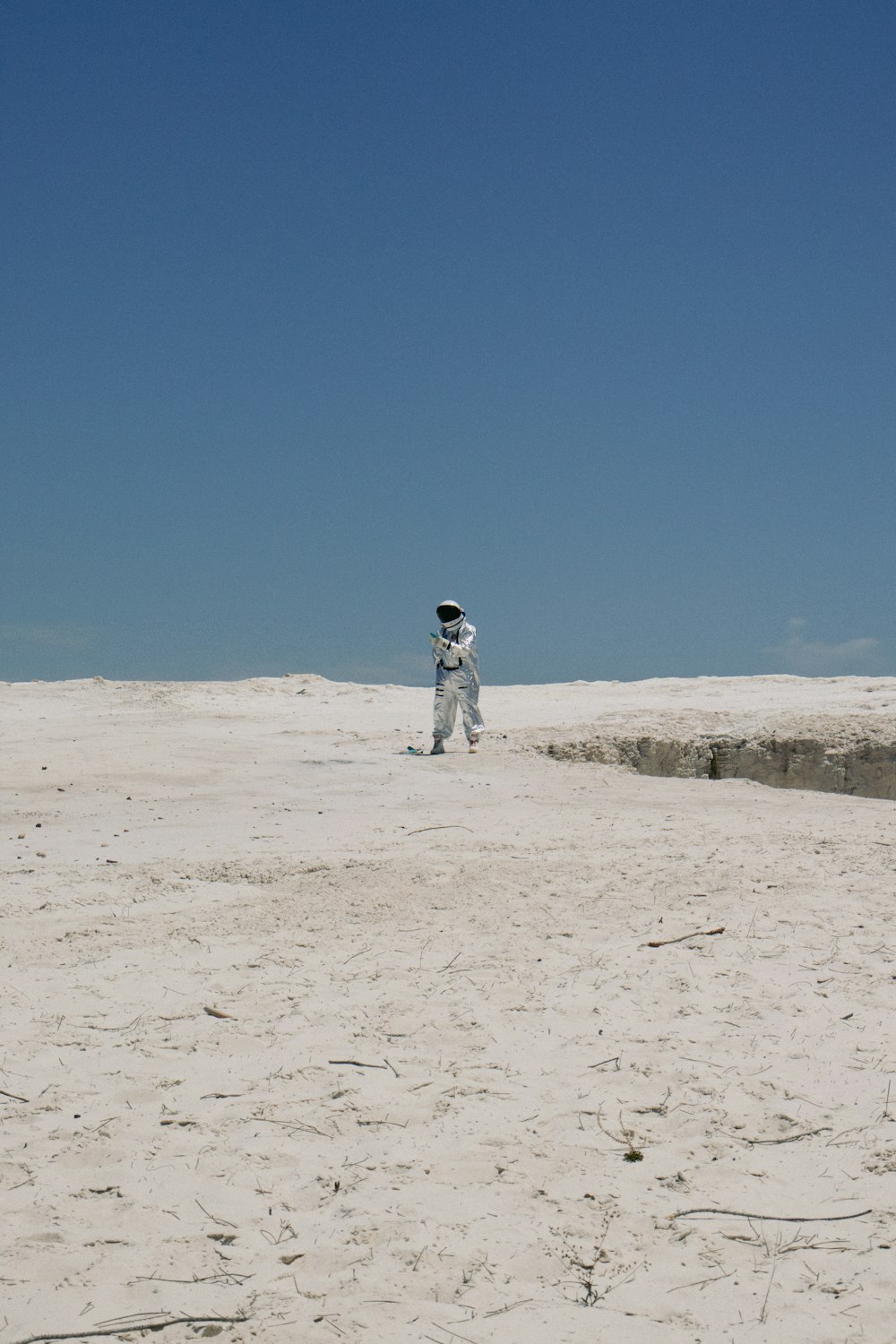 ein Mann in einem weißen Raumanzug, der im Sand steht