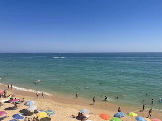 Family enjoying a sunny beach with vibrant umbrellas and clear blue water