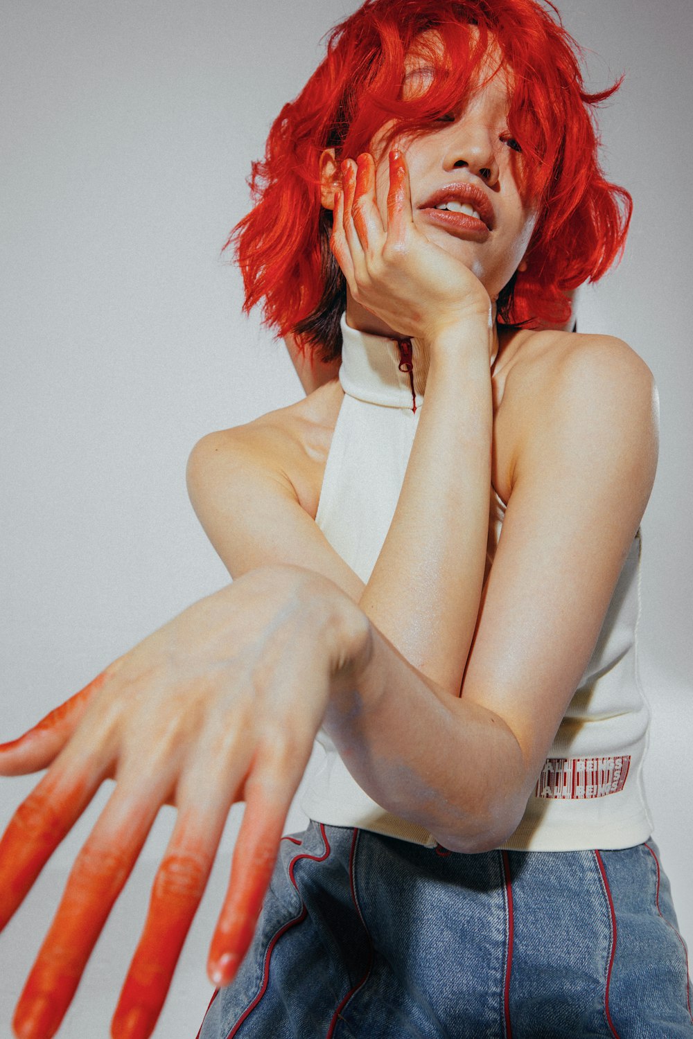a woman with red hair holding her hands up to her face