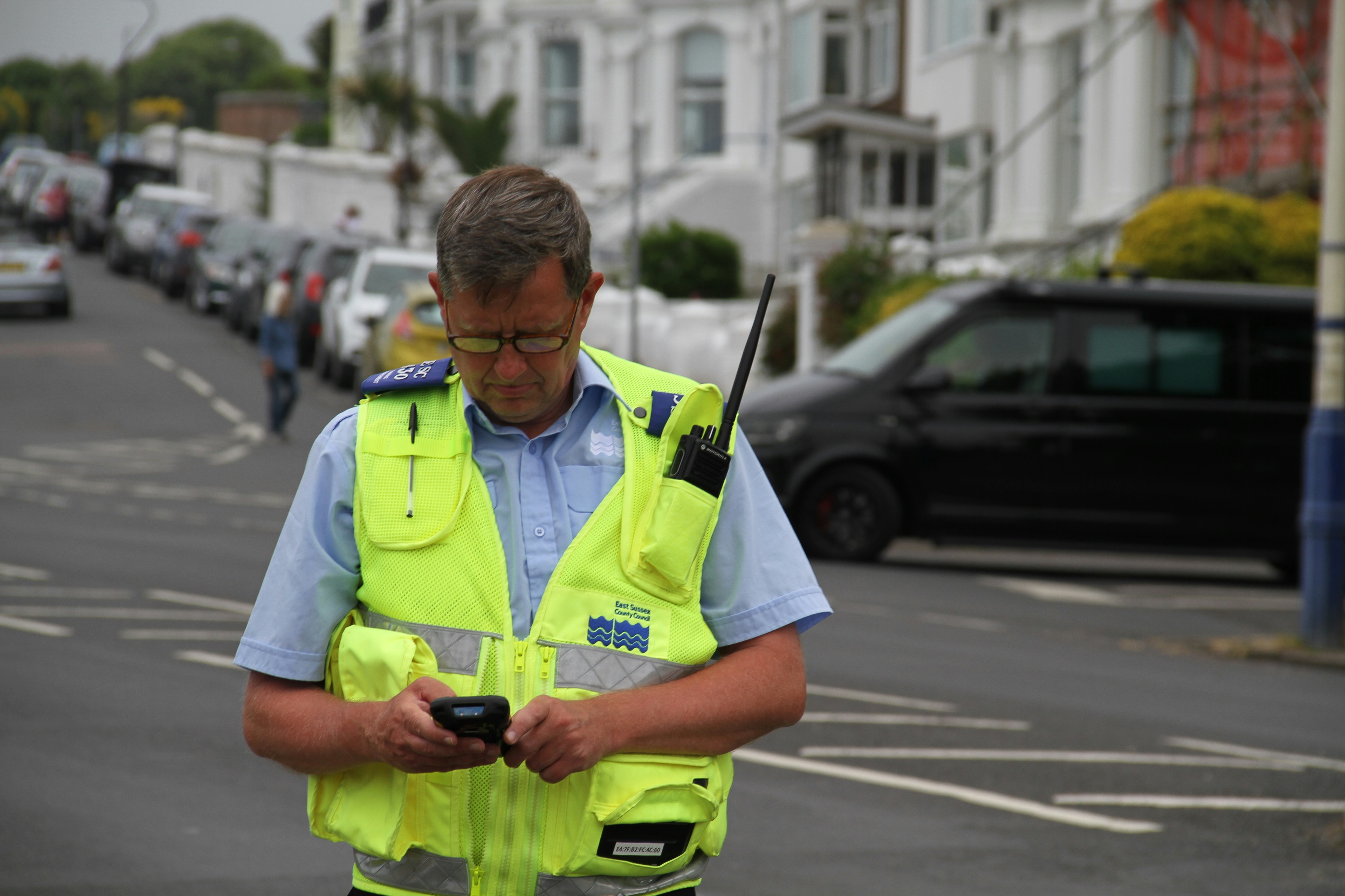 a man in a yellow vest looking at a cell phone