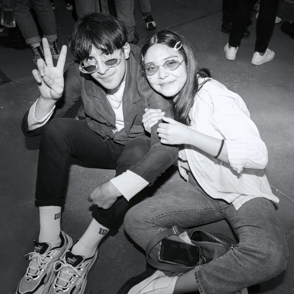 a man and woman sitting on the ground posing for a picture