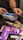 A person is using a payment terminal to complete a transaction, with hands holding a card and interacting with the device. Various snacks, including a bag of colorful gummy candies and chocolate bars in purple packaging, are placed on a dark countertop.