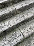 Close-up of weathered flagstone steps leading to a classic European villa entrance, showcasing natural patina and texture.