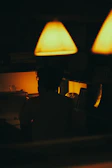A quiet study room bathed in navy blue shadows with a single gold-toned lamp casting a warm glow.