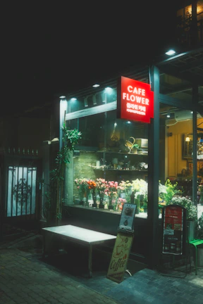 A small café owner proudly arranging fresh flowers outside her shop with a visible Google Business Profile on a tablet.