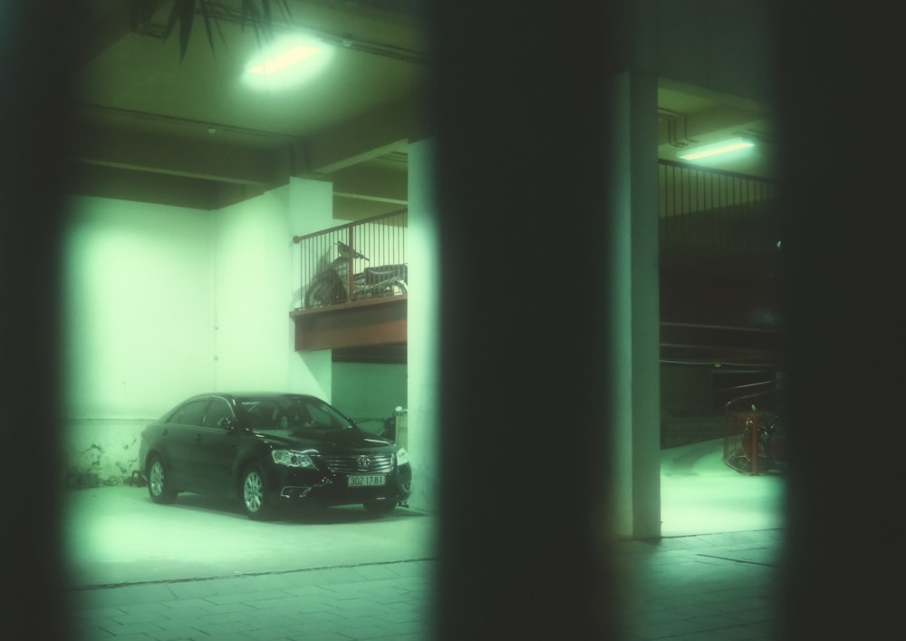 a black car parked in a garage next to a staircase