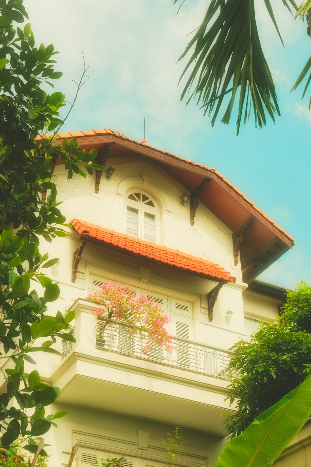 a white house with a red roof and balcony