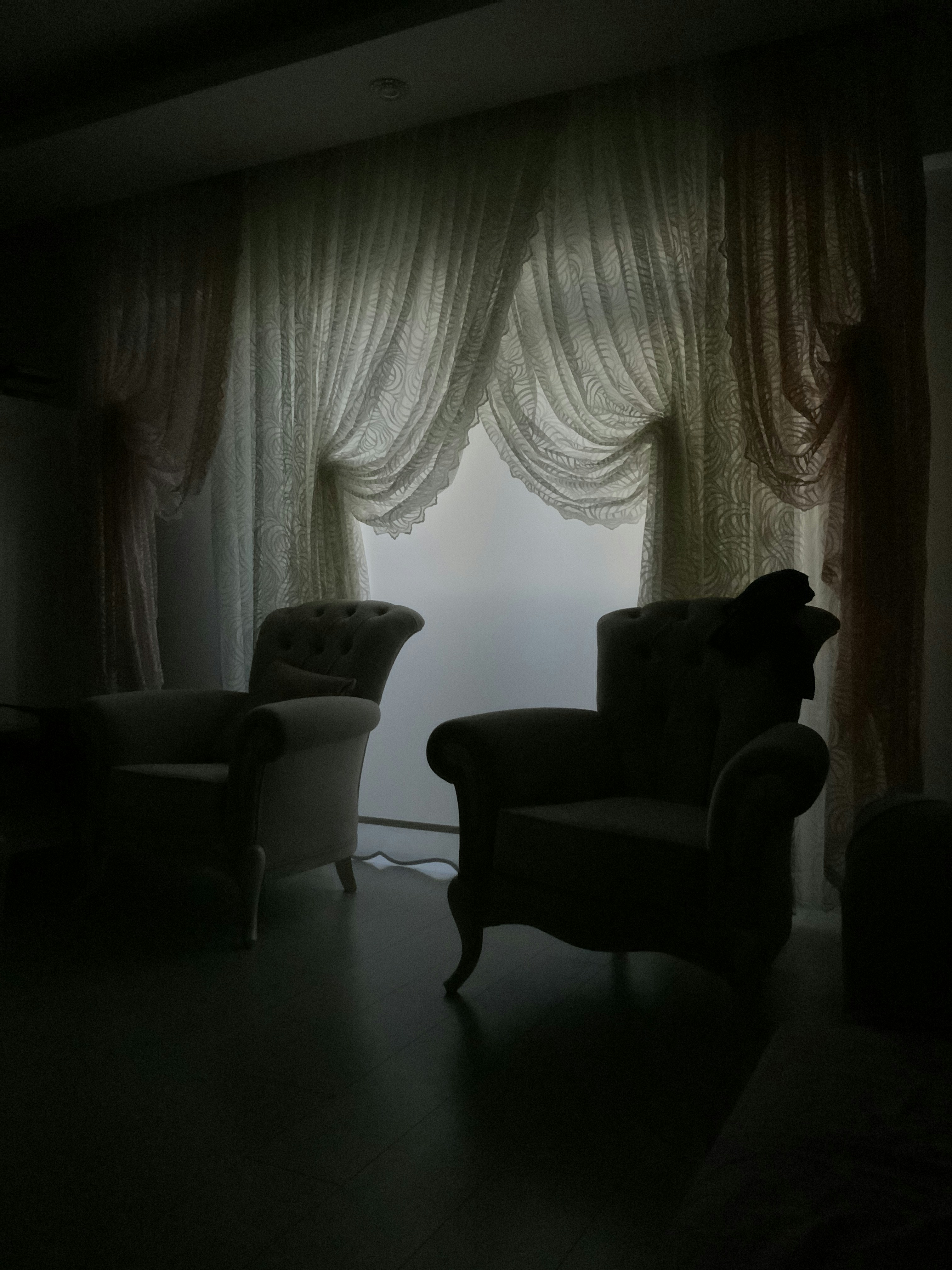 Individual therapy room with two armchairs facing each other, sheer curtains diffusing sunlight, and a small bookshelf