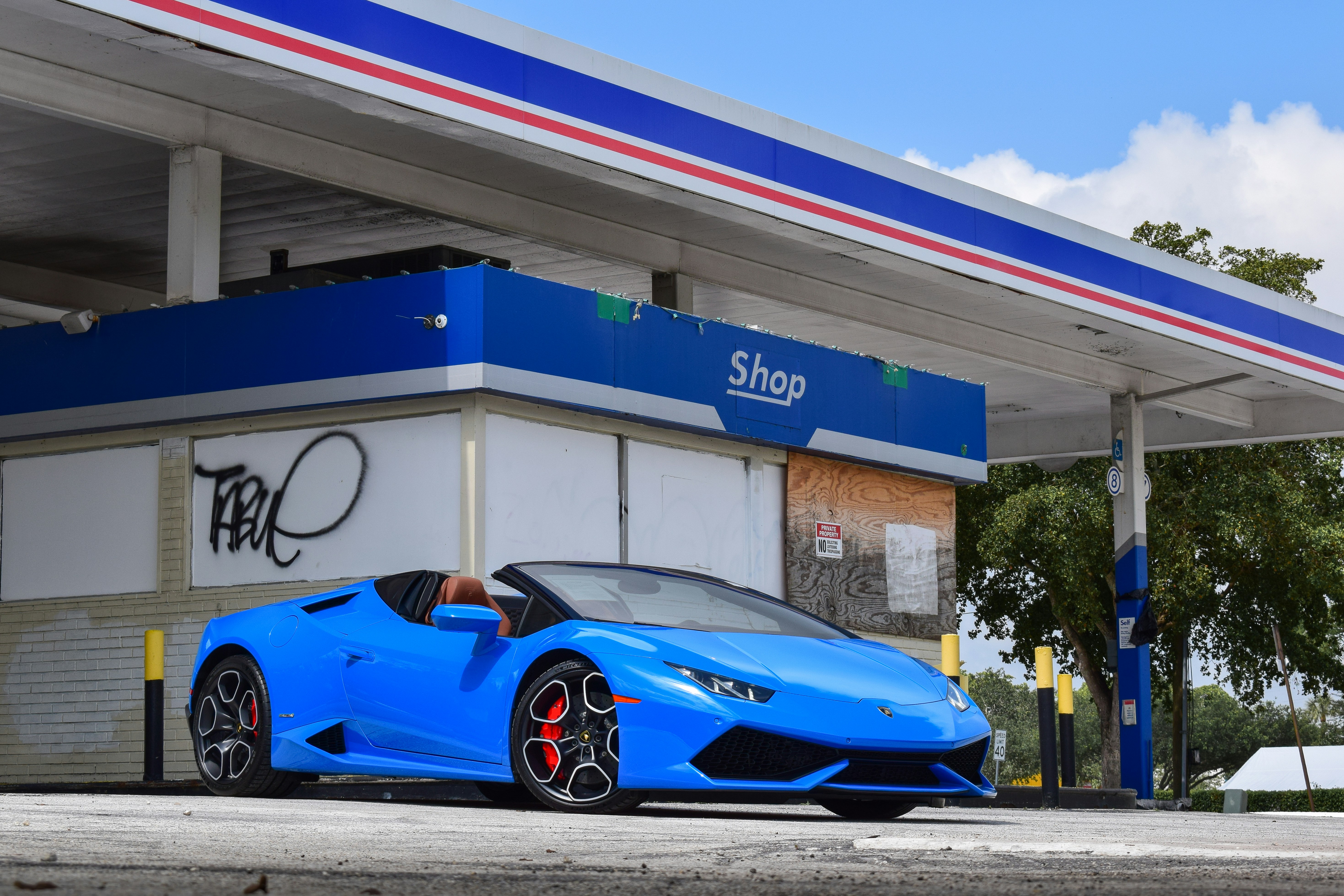 a blue sports car parked in front of a gas station