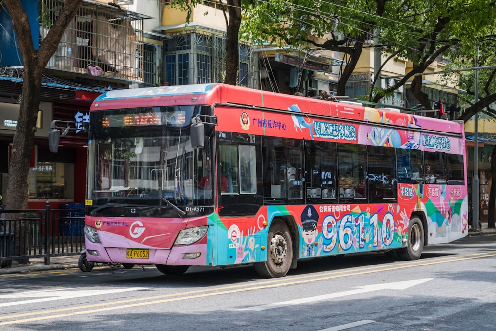 a pink and blue bus driving down a street