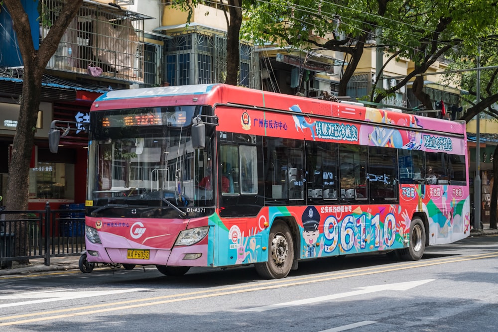 ein rosa-blauer Bus, der eine Straße entlang fährt