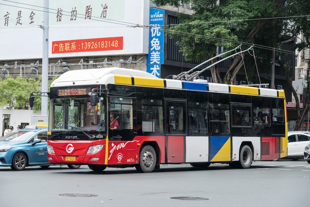 a red, yellow, and blue bus driving down a street