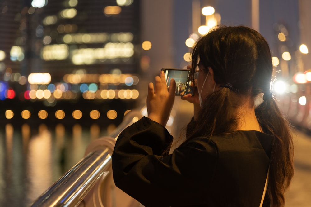 a woman taking a picture of a city at night