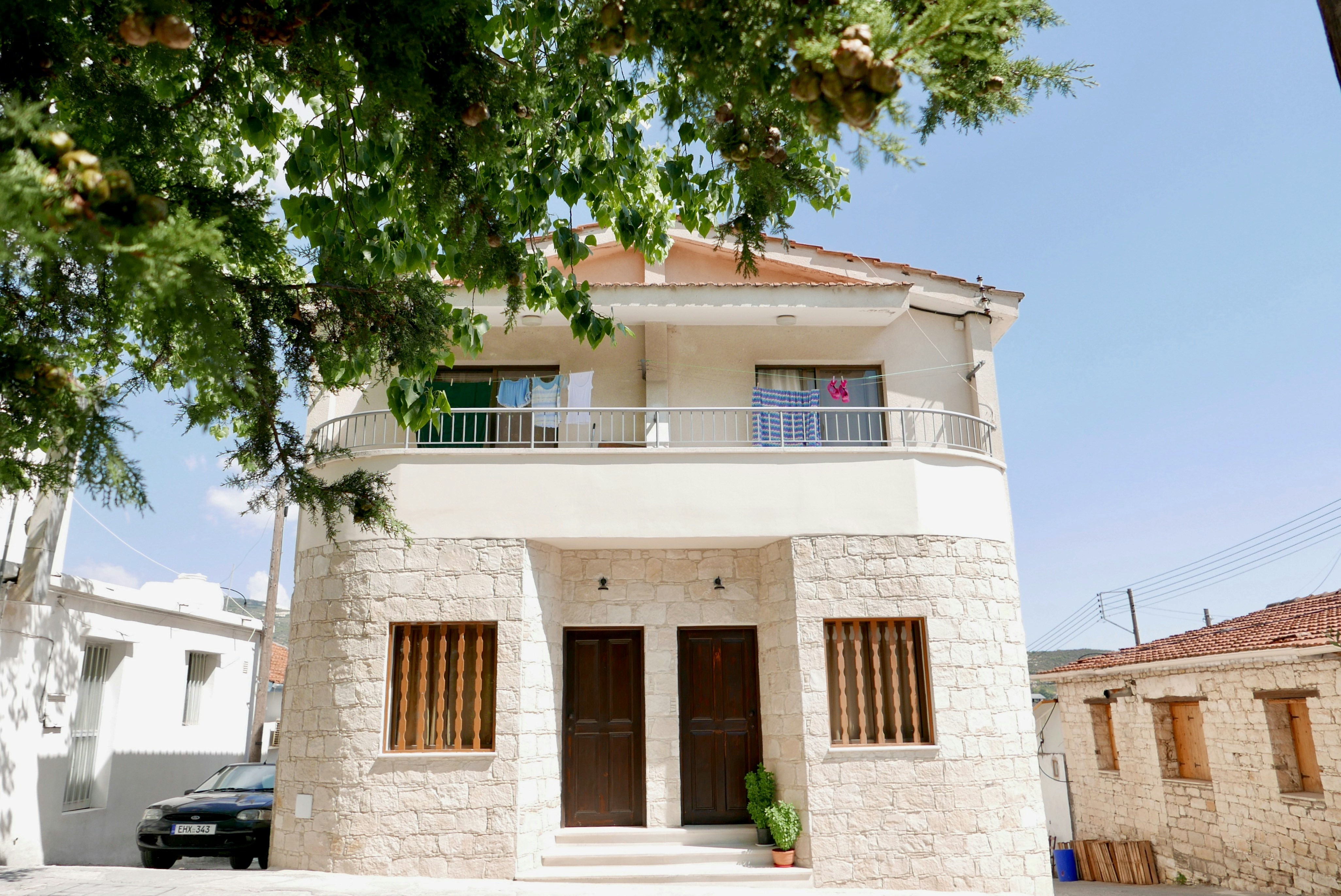 a white house with a balcony and a car parked in front of it