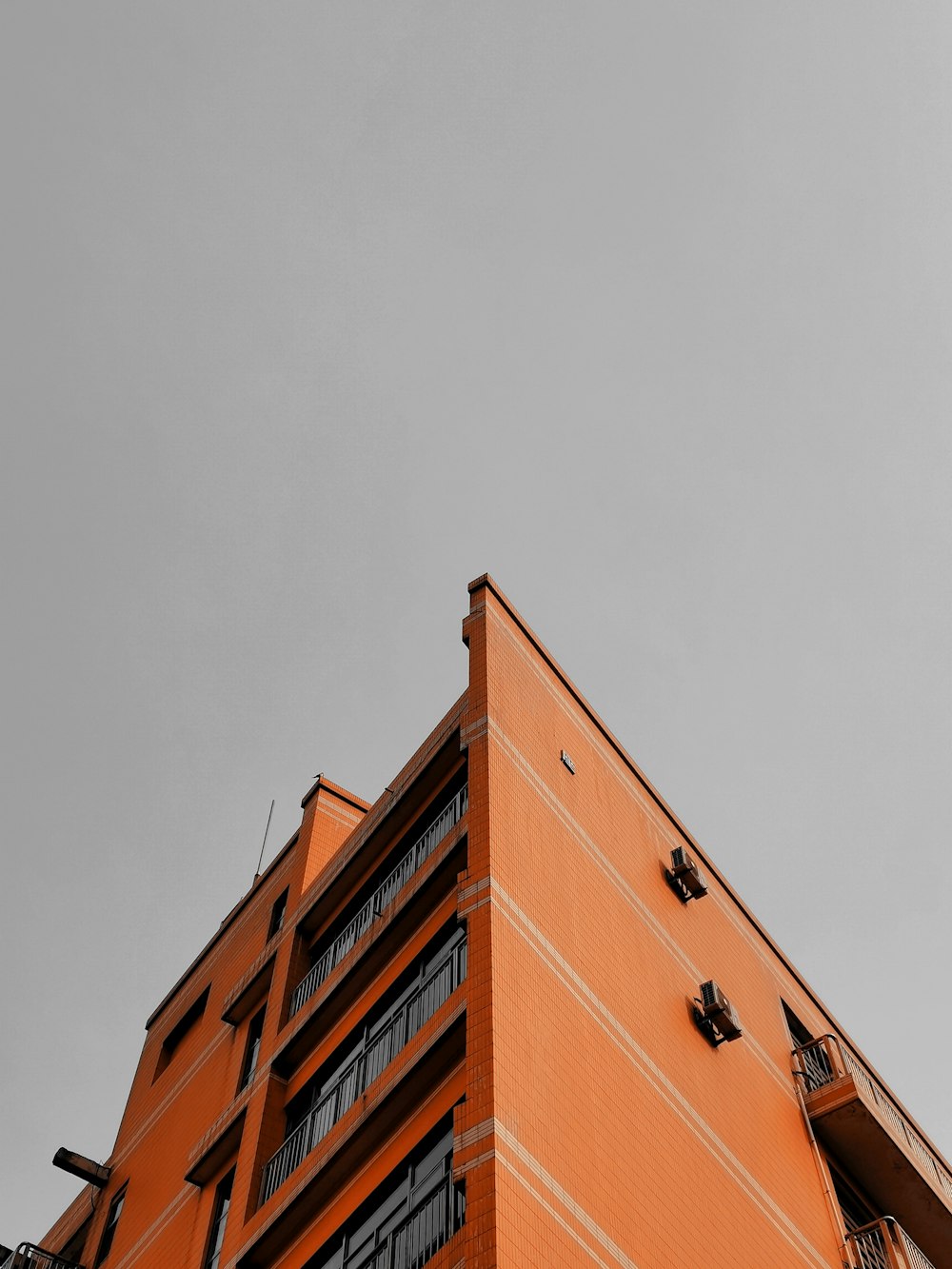 a tall orange building with a clock on it's side