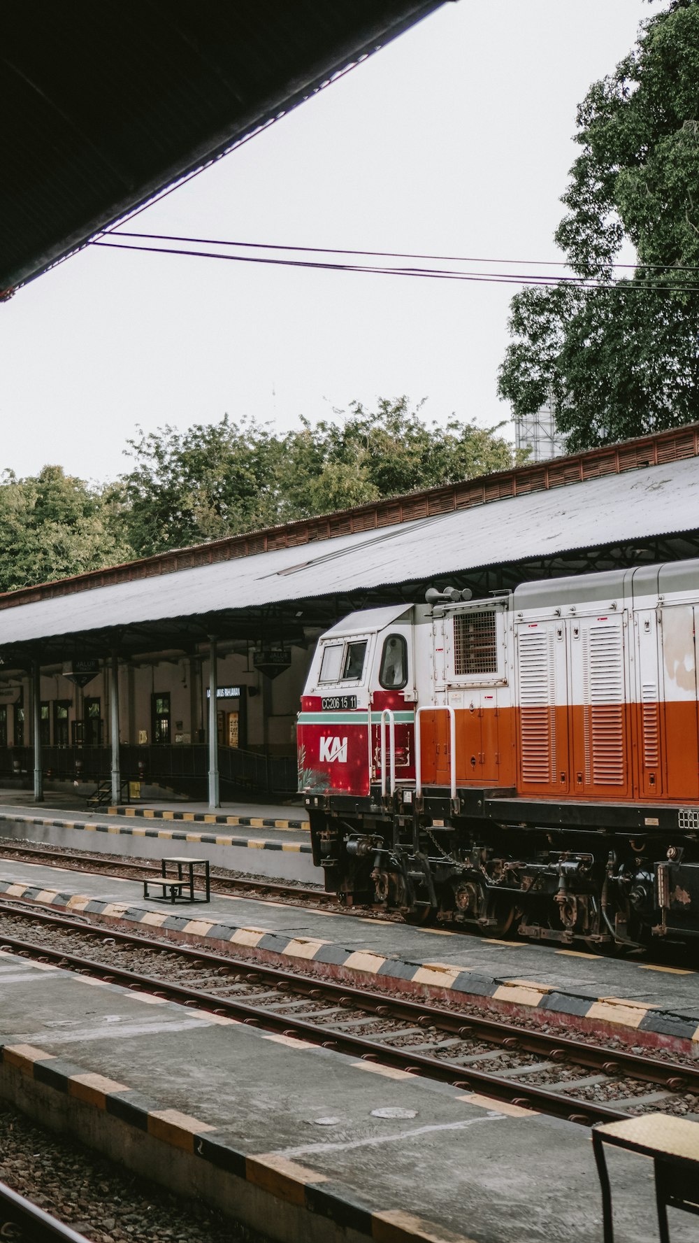um trem vermelho e branco puxando para uma estação de trem