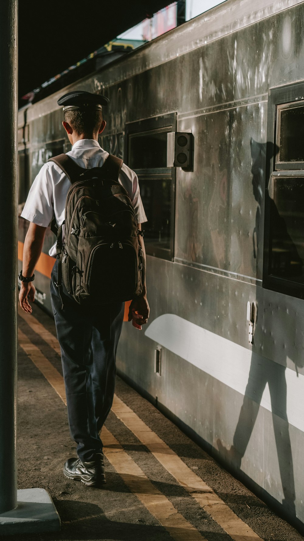 a man with a backpack walking towards a train