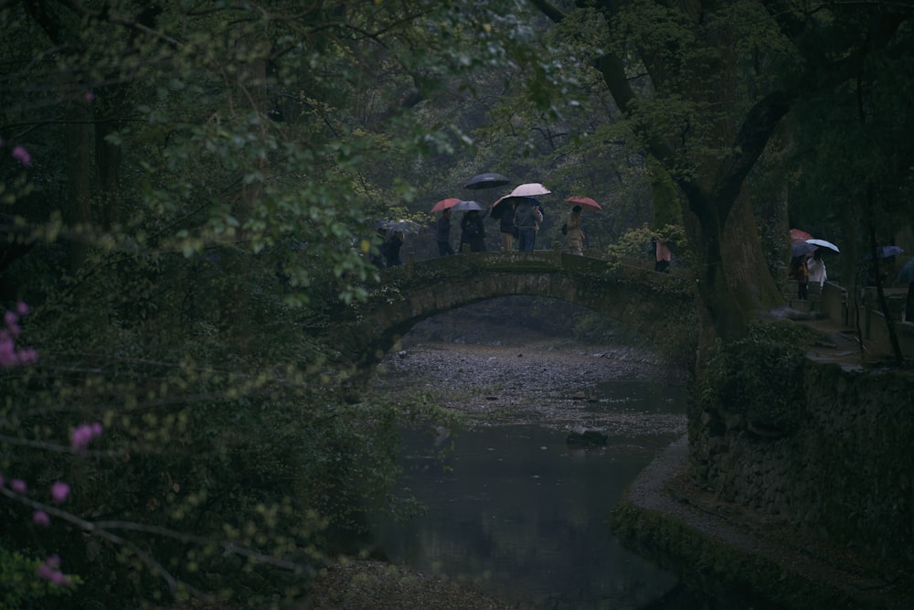 a group of people standing on a bridge holding umbrellas