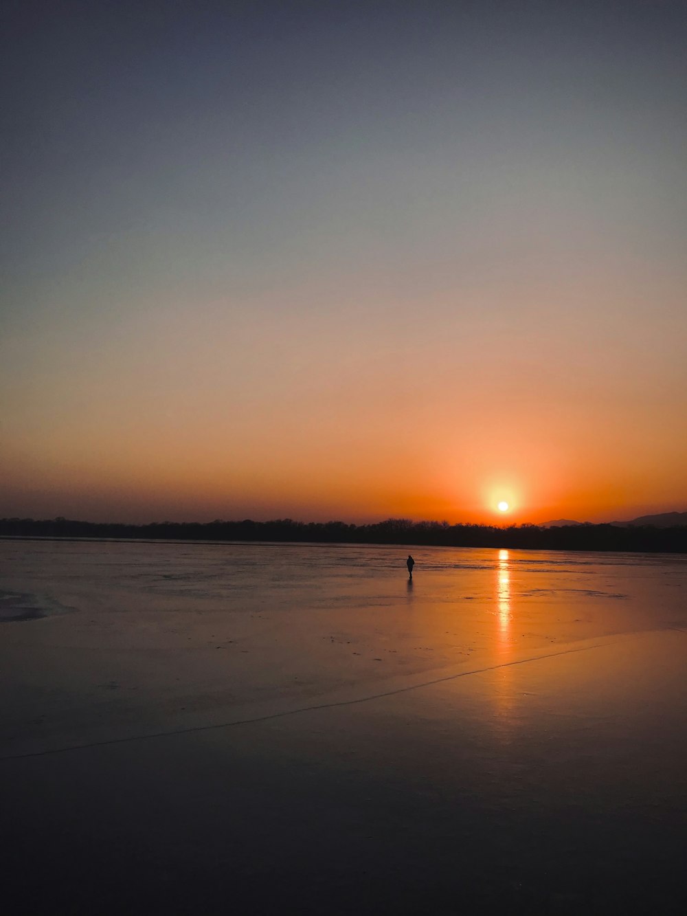 eine person, die bei sonnenuntergang an einem strand steht