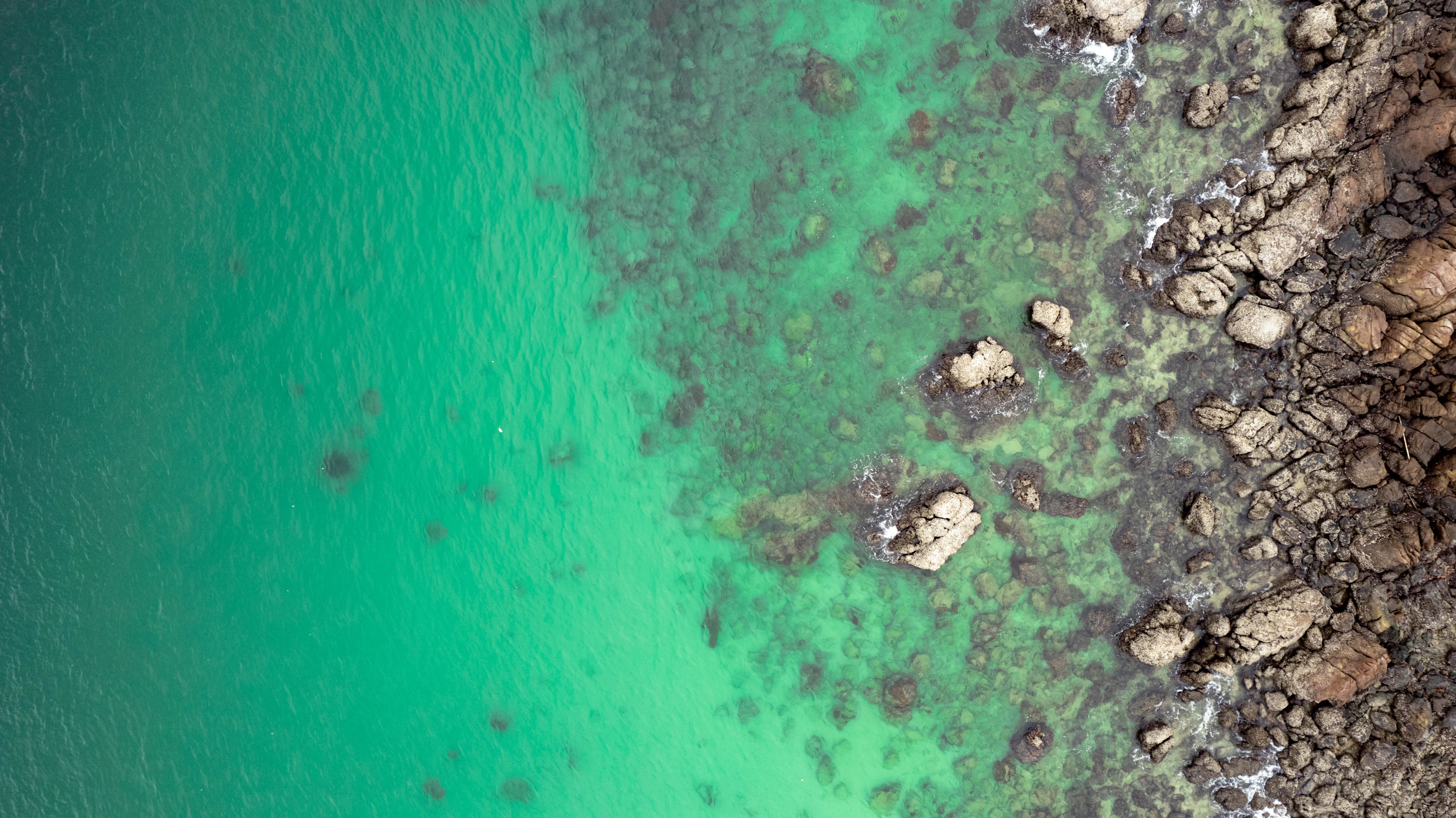 格蘭島清澈碧綠海水與自然岩岸的空中景致