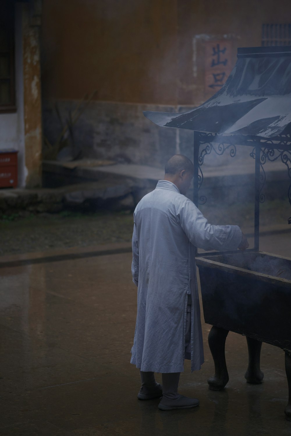 a man in a white coat standing next to a grill