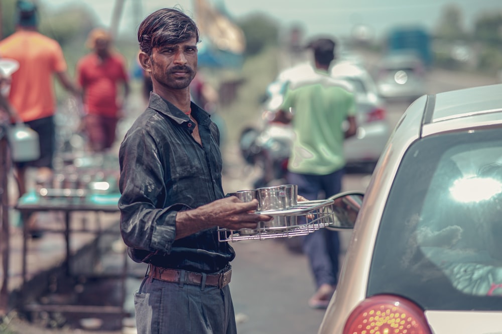 a man standing next to a car holding a tray of food