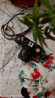 Close-up of a map, a minimalistic camera, and a soft beige scarf folded neatly beside it.