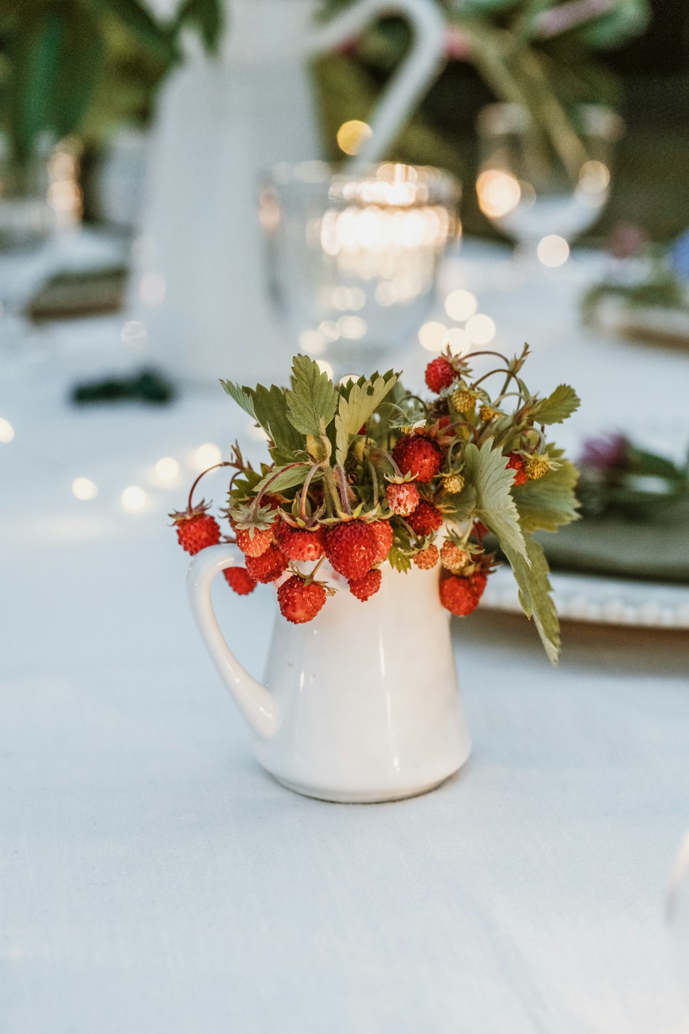 a white pitcher filled with strawberries on top of a table