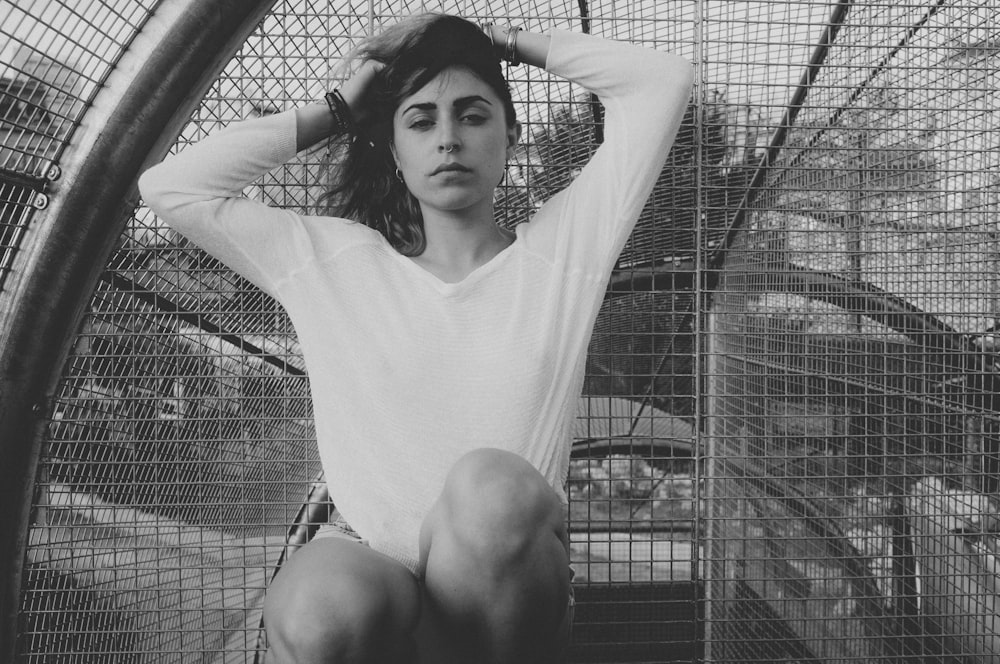 a black and white photo of a woman sitting in a cage