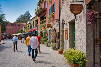 Sunlit cobblestone street lined with blooming flowers, inviting travelers to explore.
