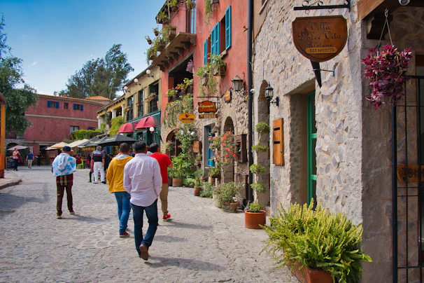 Sunlit cobblestone street lined with blooming flowers, inviting travelers to explore.