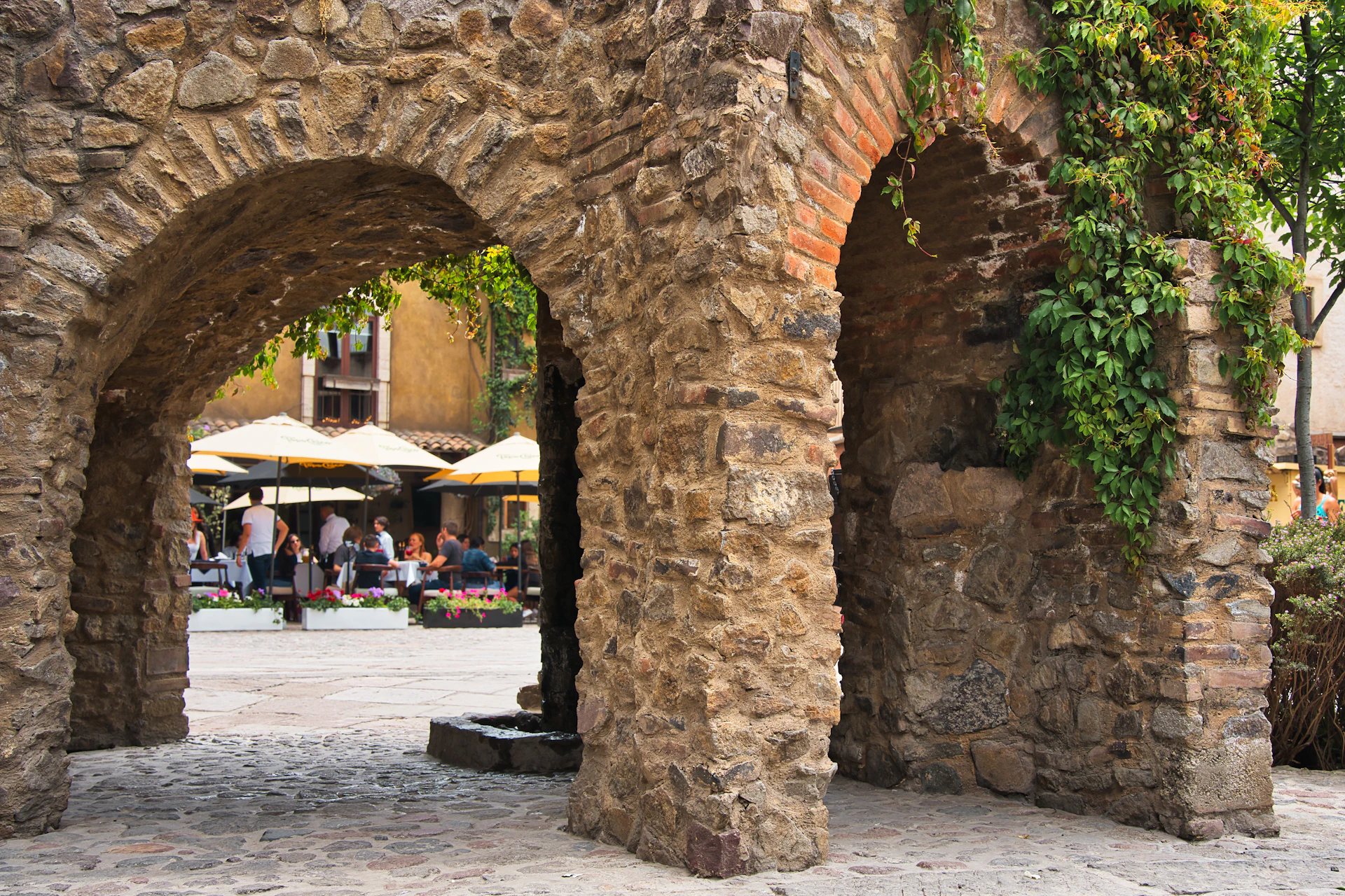 Historic stone walls of Mostarika blending with modern café furniture, capturing the spirit of Mostar.