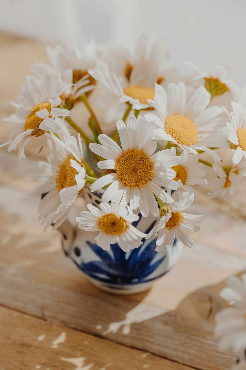 a blue and white vase filled with white and yellow flowers