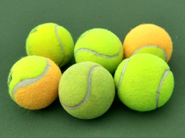 Tennis balls on a textured grey surface, minimalistic style.