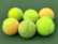 Close-up of colorful tennis balls arranged on a wooden surface.