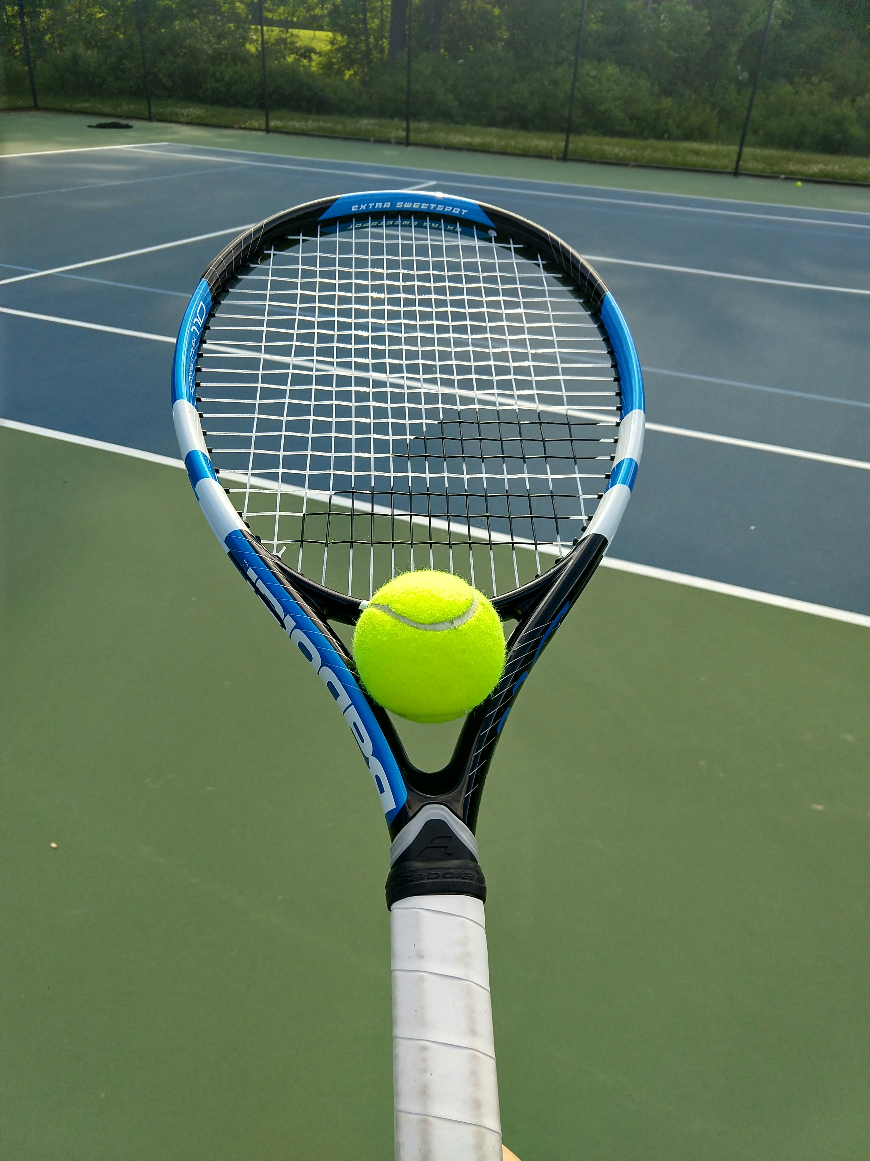 Bright green tennis court surface with tennis racket and ball, vibrant sports setting