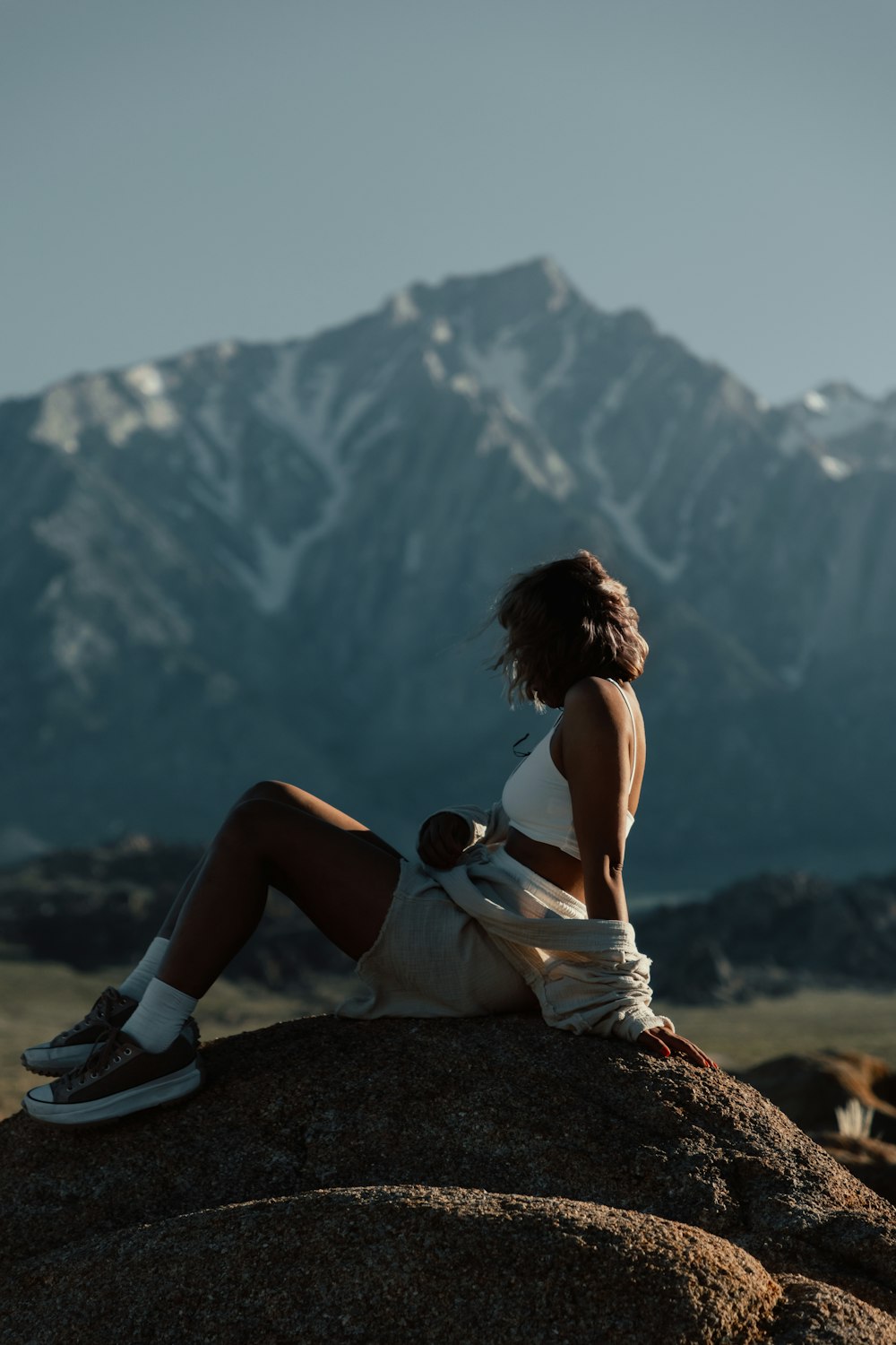 a woman sitting on top of a large rock