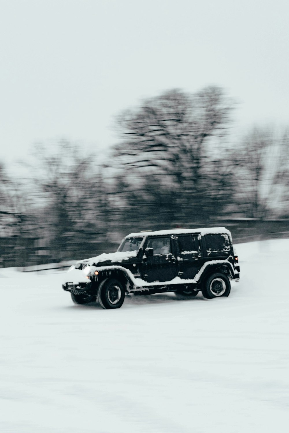 a jeep driving through a snow covered field