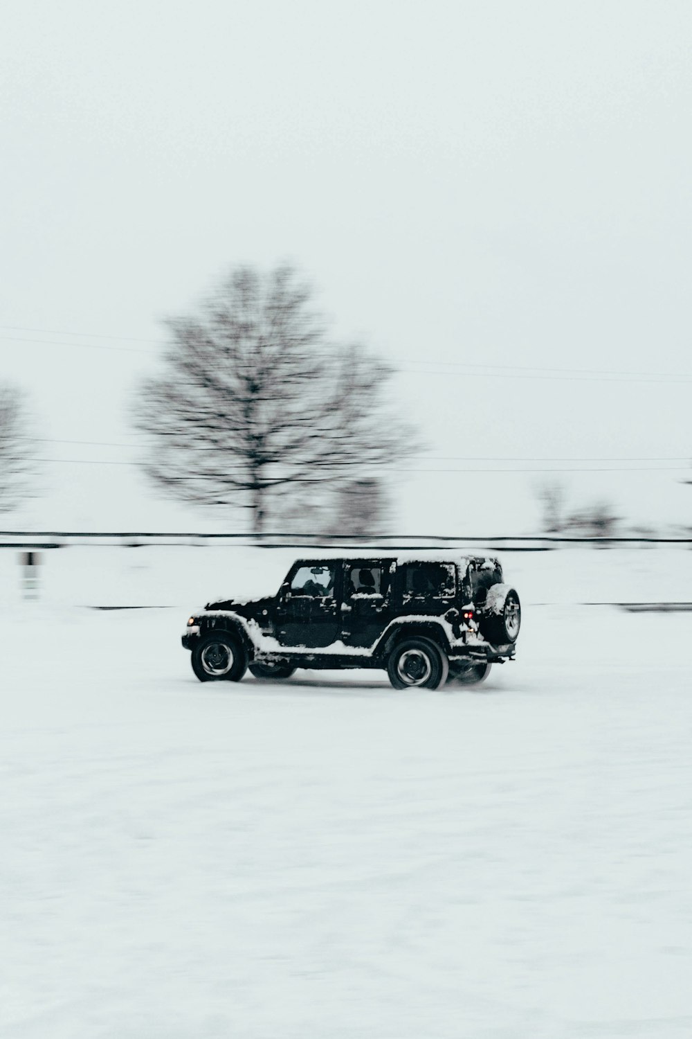 a jeep driving through a snow covered field